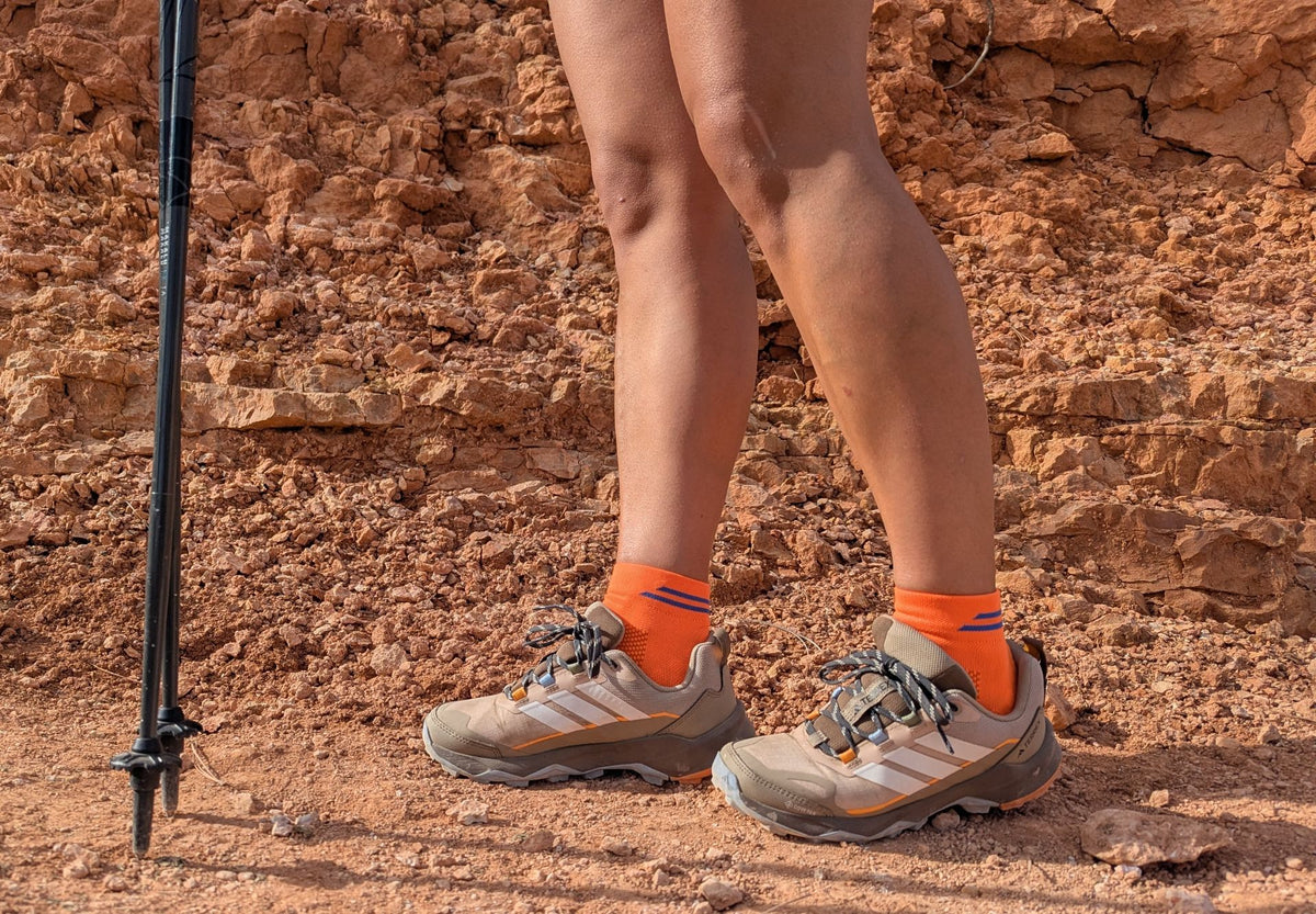 Mujer en la montaña con calcetines tecnicos de Running naranja. Modelo Bost Ondarreta