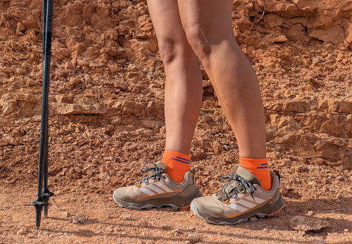 Mujer en la montaña con calcetines tecnicos de Running naranja. Modelo Bost Ondarreta